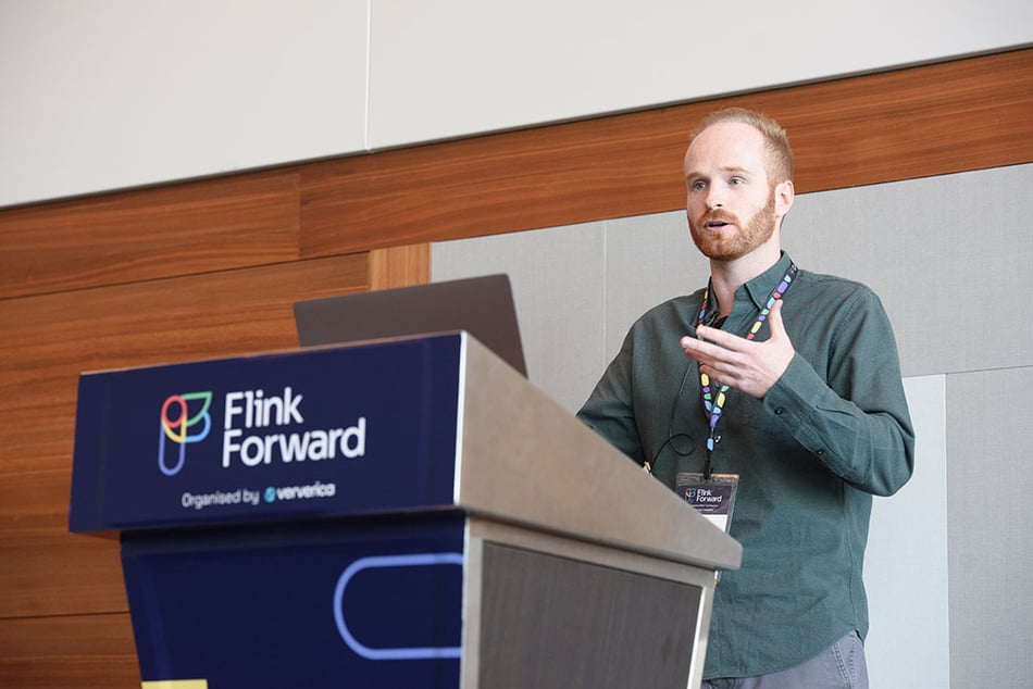 Presenter on the Flink Forward stage, standing behind a podium.